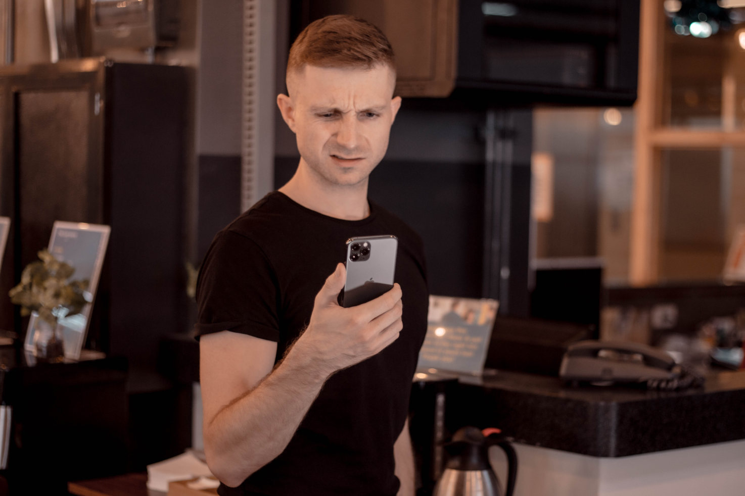 Cyril Mazur tenant un smartphone, l’air perplexe, illustrant les questions fréquentes des débutants dans les rencontres trans.