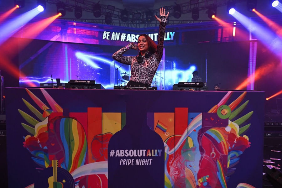 A DJ raises her hand behind a rainbow-decorated booth at Pride Night, Lalit Ashok Bangalore.