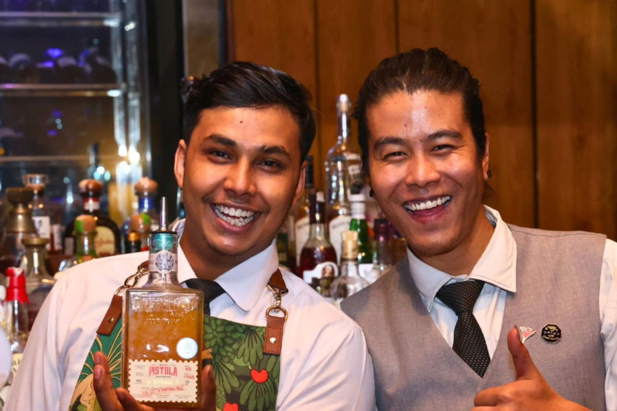 Smiling staff at Taj Gurugram holding a spirit bottle during Tease x PCO bar night.