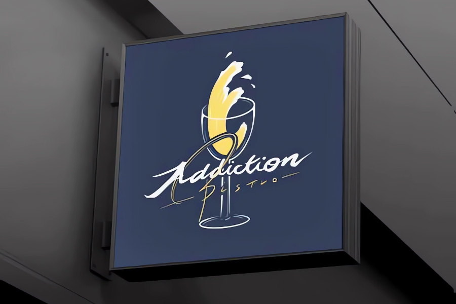 牆上掛著一個方形招牌，上面印有「Addiction Bistro」的標誌，採用現代草書字體設計，並搭配葡萄酒圖案。