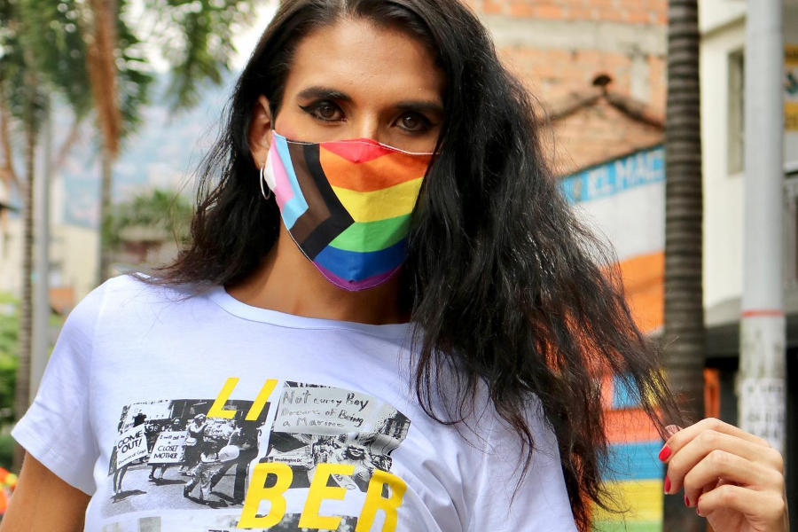 Persona en la calle Barbacoas de Medellín con una máscara colorida del orgullo y una camiseta blanca con imágenes LGBT.