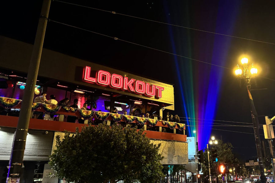 Exterior of Lookout bar in San Francisco at night with neon signage, balcony crowd, and colourful sky lights.